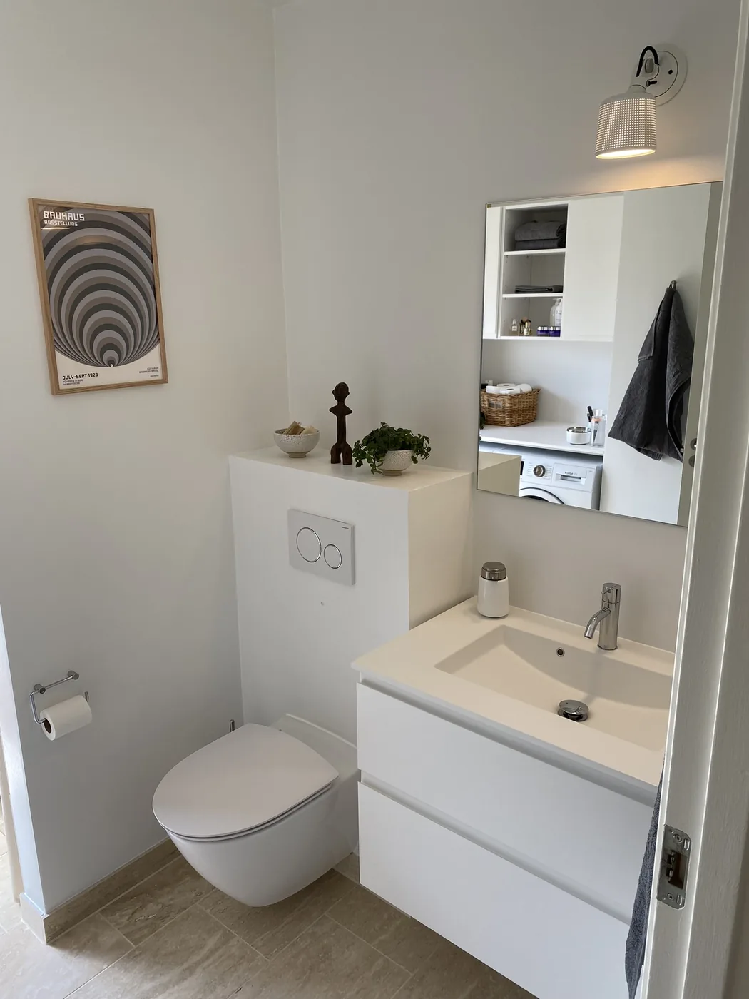 Badeværelse efter renovering med væghængt toilet og hvid vaskeplads