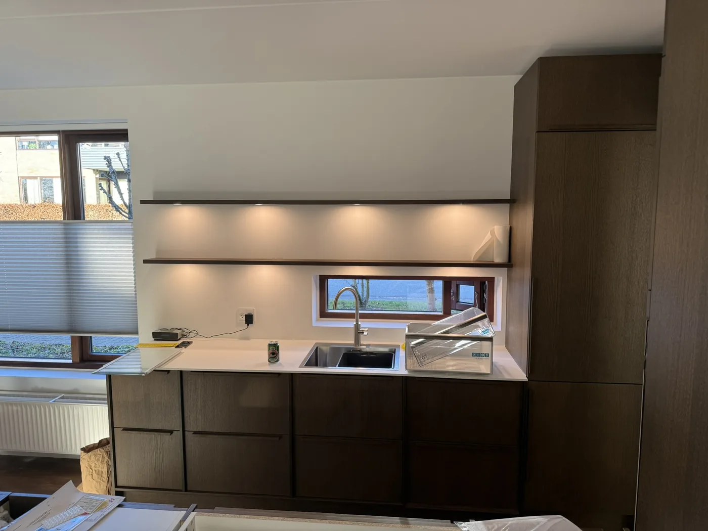 Køkken efter renovering med mørke skabe og vindue over vasken